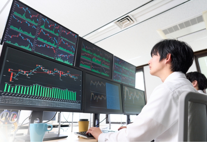 パソコンで株価グラフを見つめる男性