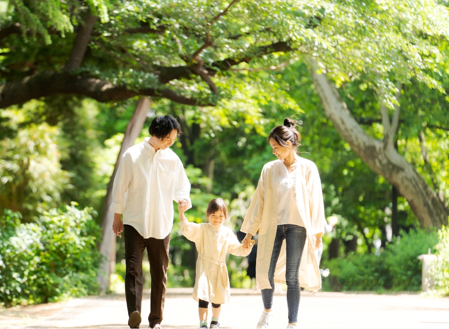 森の中を、子どもの両手をつないで歩く夫婦