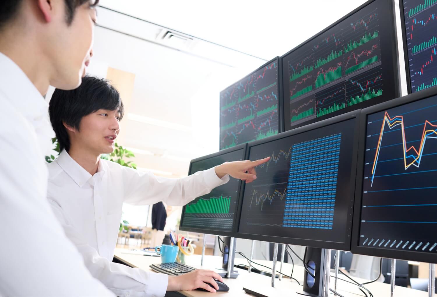 画面を見ながら先輩に教えてもらう男性ディーラー