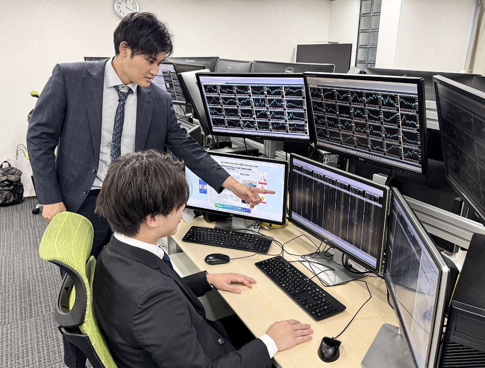 画面を見ながら先輩に教えてもらう男性ディーラー