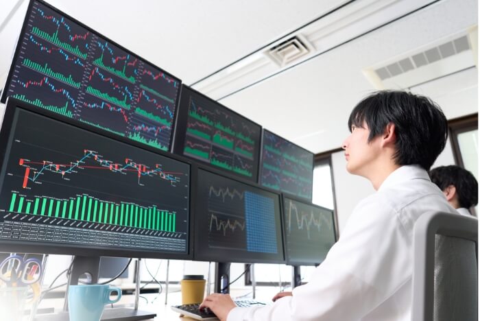 複数のモニターで仮想売買する男性の後ろ姿