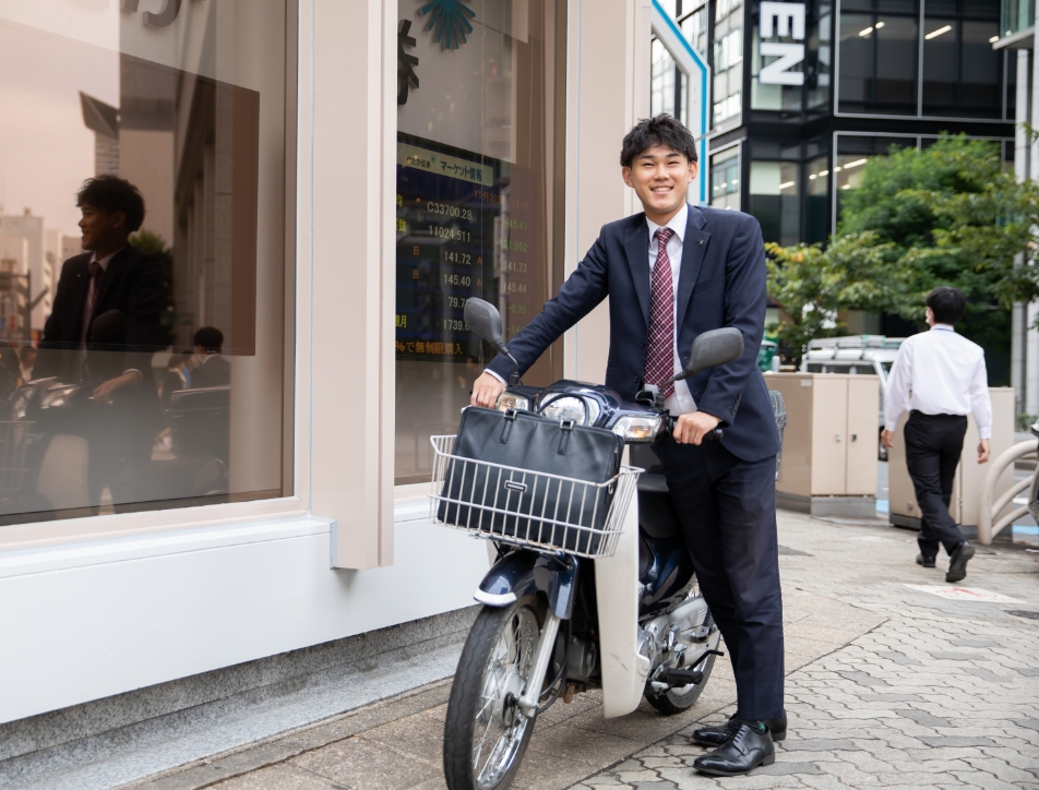 通勤用バイクを手で押す営業職の男性社員