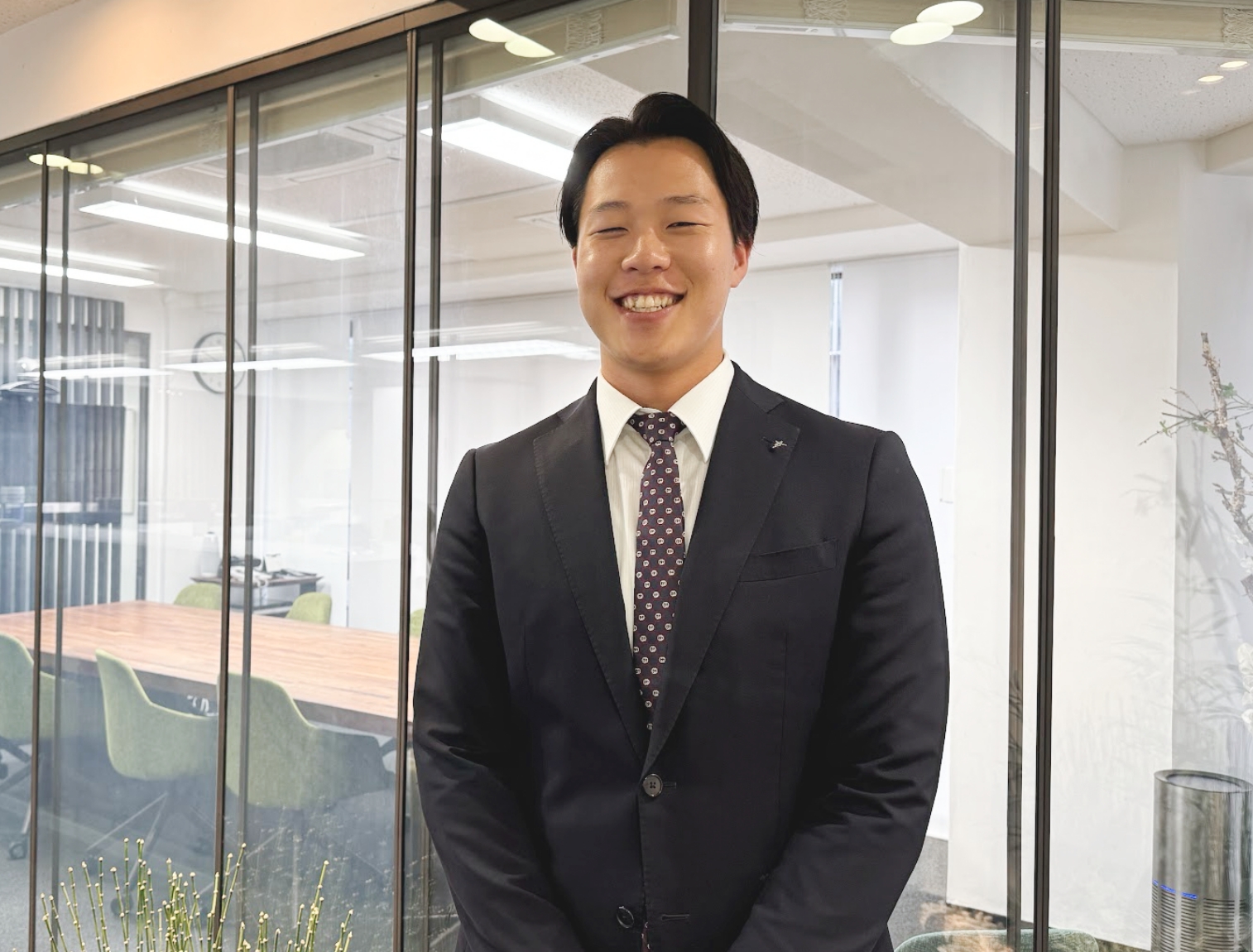 スーツ姿で笑顔を見せる営業職の男性社員