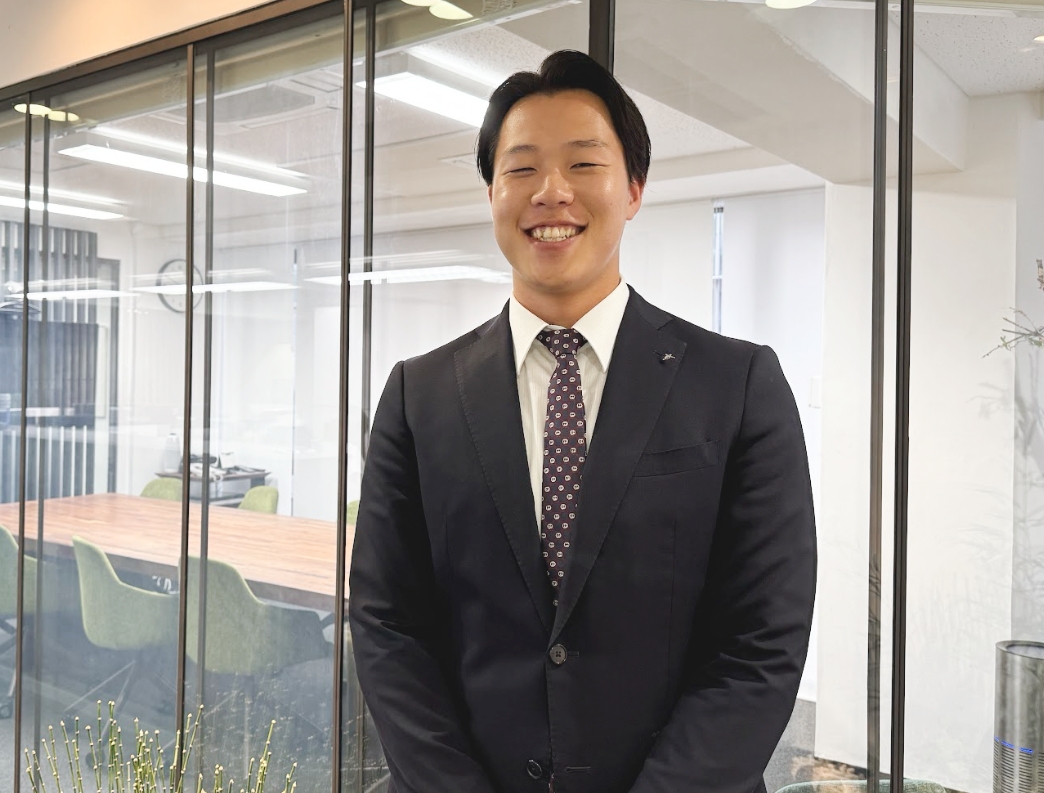 スーツ姿で笑顔を見せる営業職の男性社員