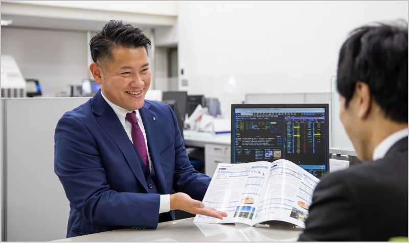 パンフレットでクライアントに説明しているスーツ姿の男性